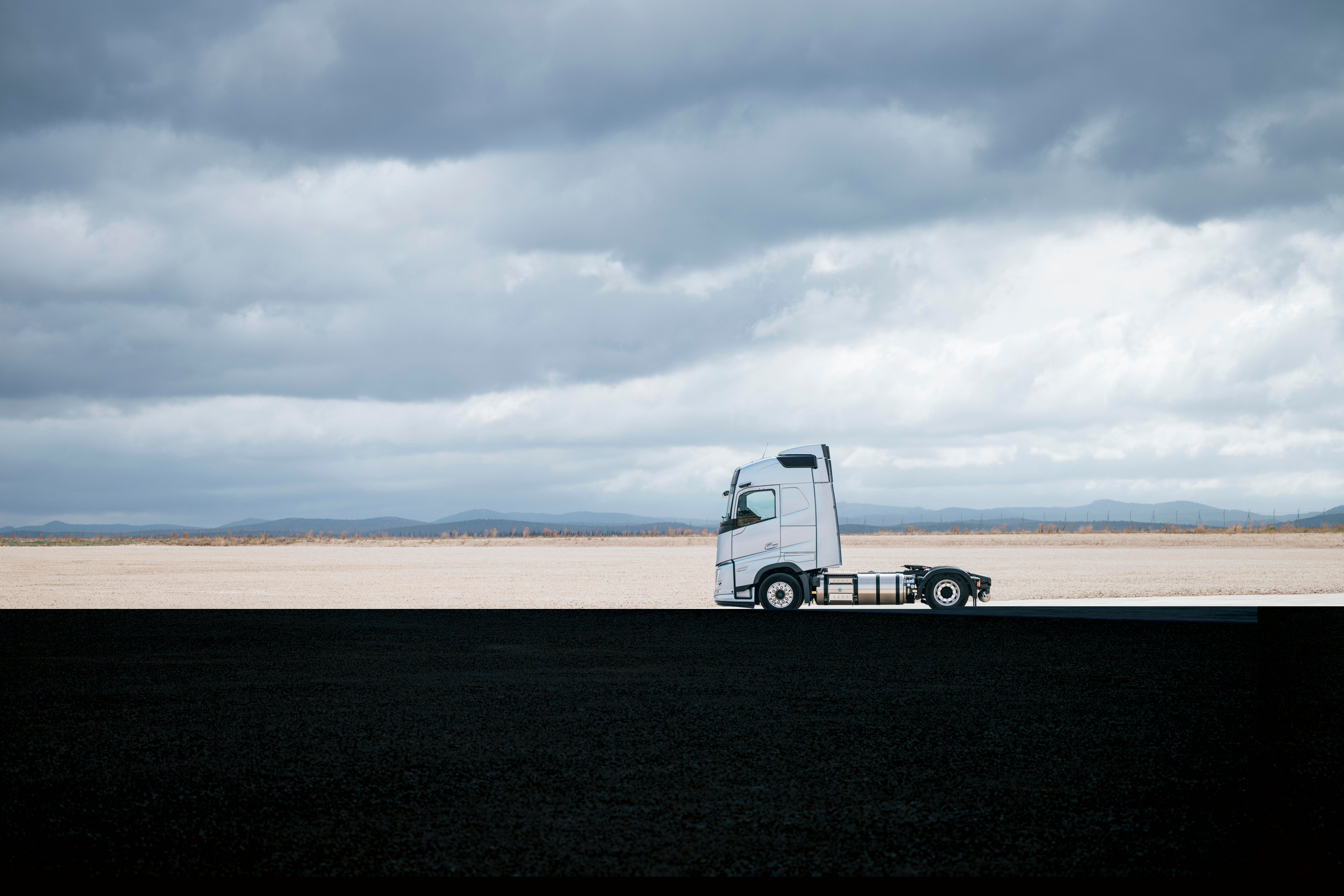 Vedere laterală a unui camion Volvo parcat într-un peisaj deschis, sub un cer înnorat, cu întinderi vaste și decoruri minime.